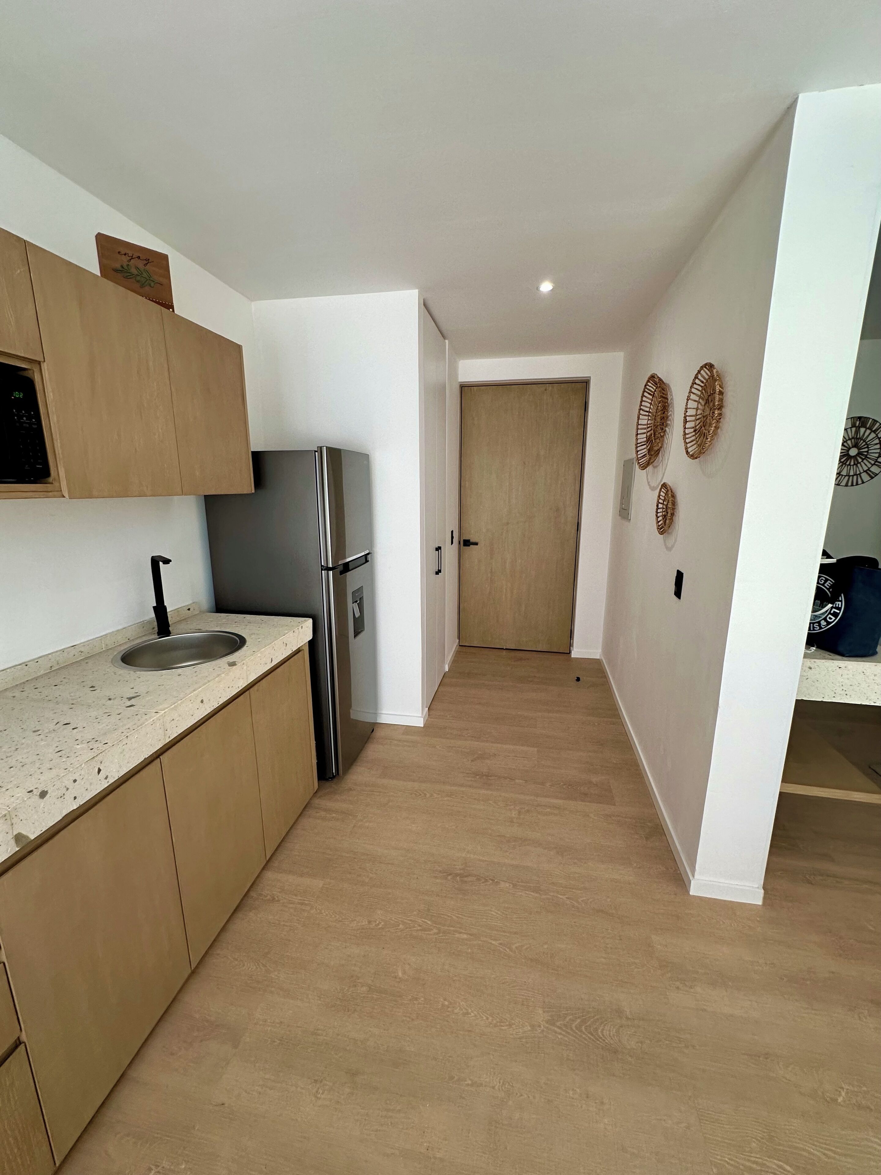 A modern kitchen with wooden cabinets, a stainless steel refrigerator, and a sink.