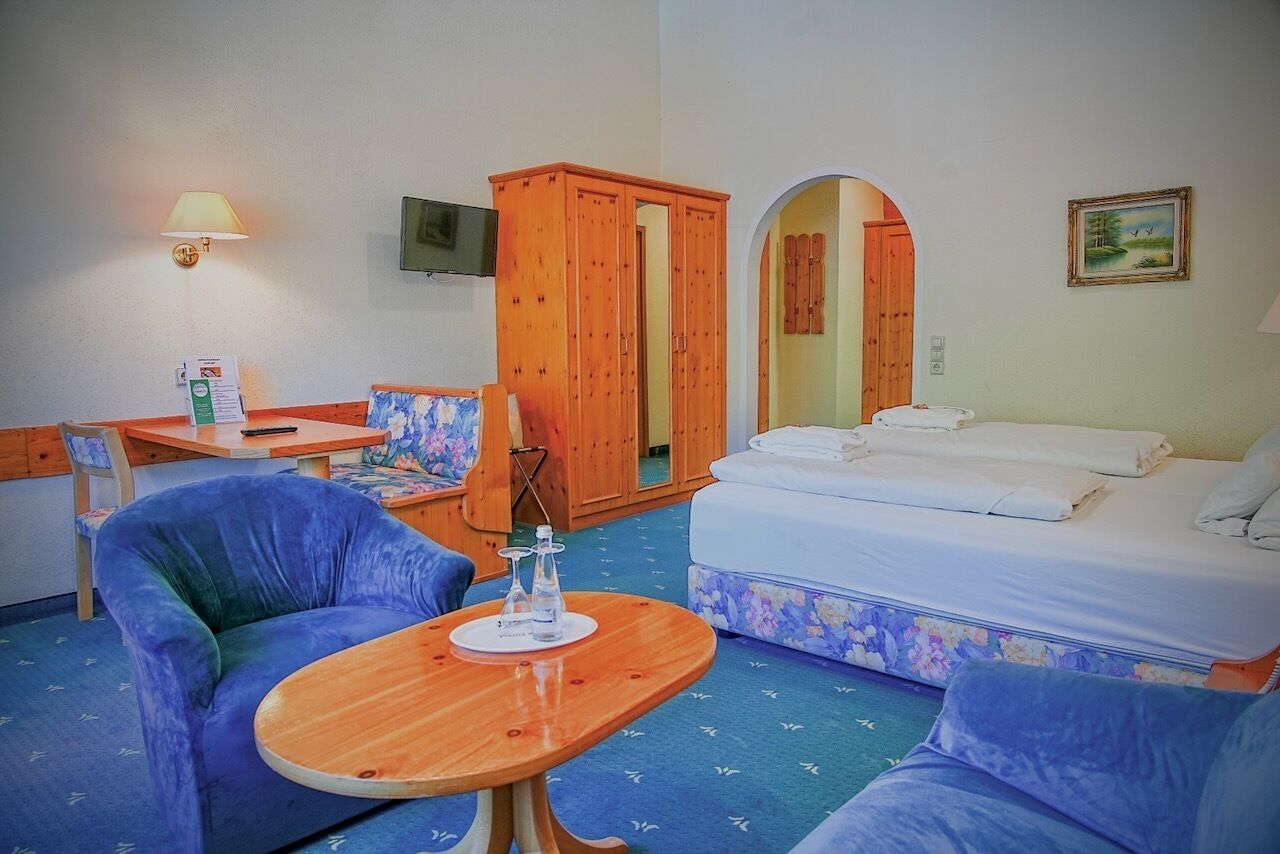 Ein Hotelzimmer mit Bett, Schreibtisch, Stuhl, Tisch, Fernseher und Kleiderschrank.