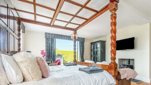 A four-poster bed with a view of a green field through a large window. - Escape to our luxury cottage in Ganton, near Scarborough. (Ganton, near Scarborough)