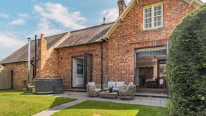 A brick house with a patio, outdoor seating, and a visible window. - Escape to our luxury cottage in Ganton, near Scarborough. (Ganton, near Scarborough)