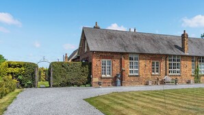 A traditional brick house with a gravel driveway and a well-maintained lawn. - Escape to our luxury cottage in Ganton, near Scarborough. (Ganton, near Scarborough)