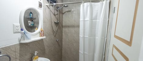 A bathroom with a shower, a sink, a mirror, and a towel rack.