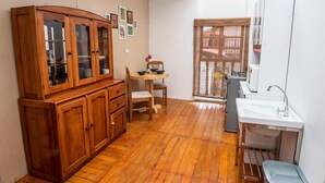 A compact kitchen with wooden cabinets, a dining table, and a sink. - Alojamiento en Centro Histórico Cusco (Cusco)
