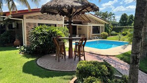 A backyard with a swimming pool, a thatched-roof structure, and a brick patio. - Seasonal House (Santa Cruz de la Sierra)