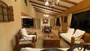 A spacious living room with a high ceiling, wooden beams, a chandelier, and a dining area in the background. - Seasonal House (Santa Cruz de la Sierra)