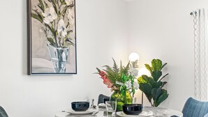Un comedor con una mesa redonda, cuencos negros y un florero con flores.