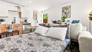 Un dormitorio moderno con una cama grande, un escritorio y una kitchenette.