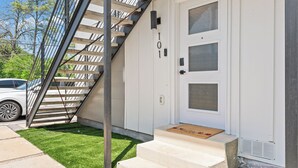 Una casa moderna con fachada blanca, una escalera que lleva a la entrada y un coche en la entrada.