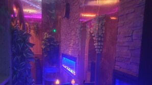 A dimly lit room with brick walls, two aquariums, and a seating area with chairs.