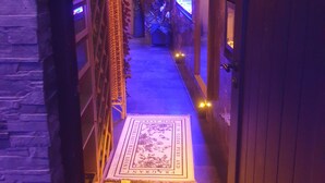 A narrow hallway with a patterned rug, decorative panels, and a blue-lit aquarium.