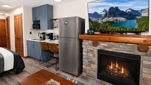 Een moderne keuken met een ingebouwde magnetron, een koelkast en een eethoek met twee stoelen.