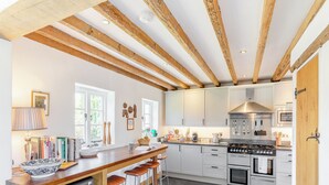 A kitchen with a central island, bar stools, a stove, oven, and a dishwasher.