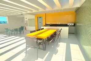 Una cocina moderna con salpicadero amarillo, un comedor con una mesa larga y sillas, y vista al exterior a través de una ventana.