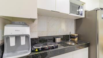 A kitchen with a water dispenser, a stove, a microwave, and a refrigerator.