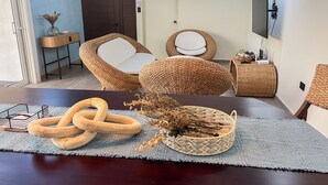 A living room with a dark wooden table, wicker furniture, and a television mounted on the wall. - A paradise in Playa Dorada: Modern home just steps from the beach. (Barra de Santiago)