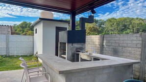An outdoor kitchen area with a concrete countertop, a built-in grill, and a sink. - A paradise in Playa Dorada: Modern home just steps from the beach. (Barra de Santiago)
