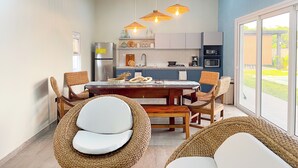 A modern kitchen with a dining area, featuring wicker chairs, a wooden table, and pendant lights. - A paradise in Playa Dorada: Modern home just steps from the beach. (Barra de Santiago)
