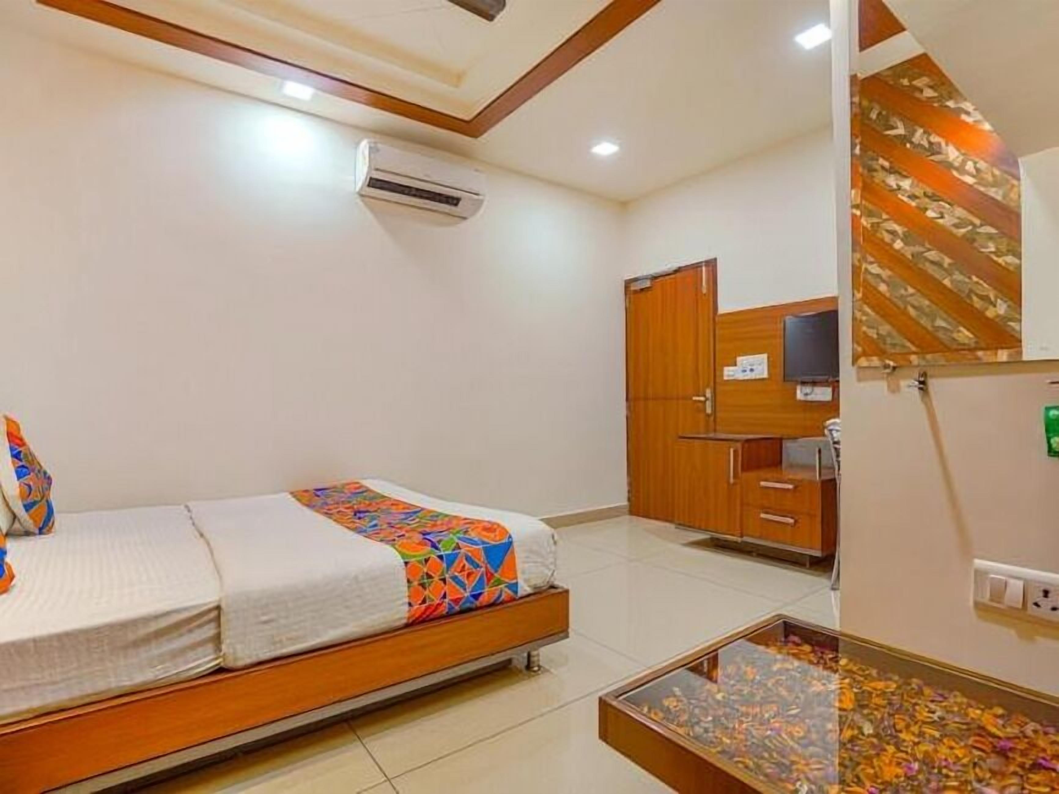 Habitación de hotel con una cama, una mesita con un adorno, un armario y un equipo de aire acondicionado.