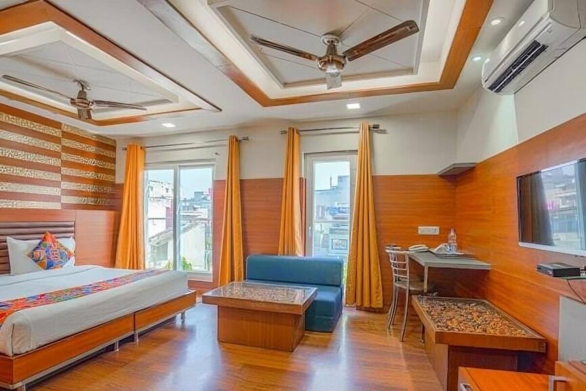 A hotel room with a bed, a sofa, a desk, and a TV.