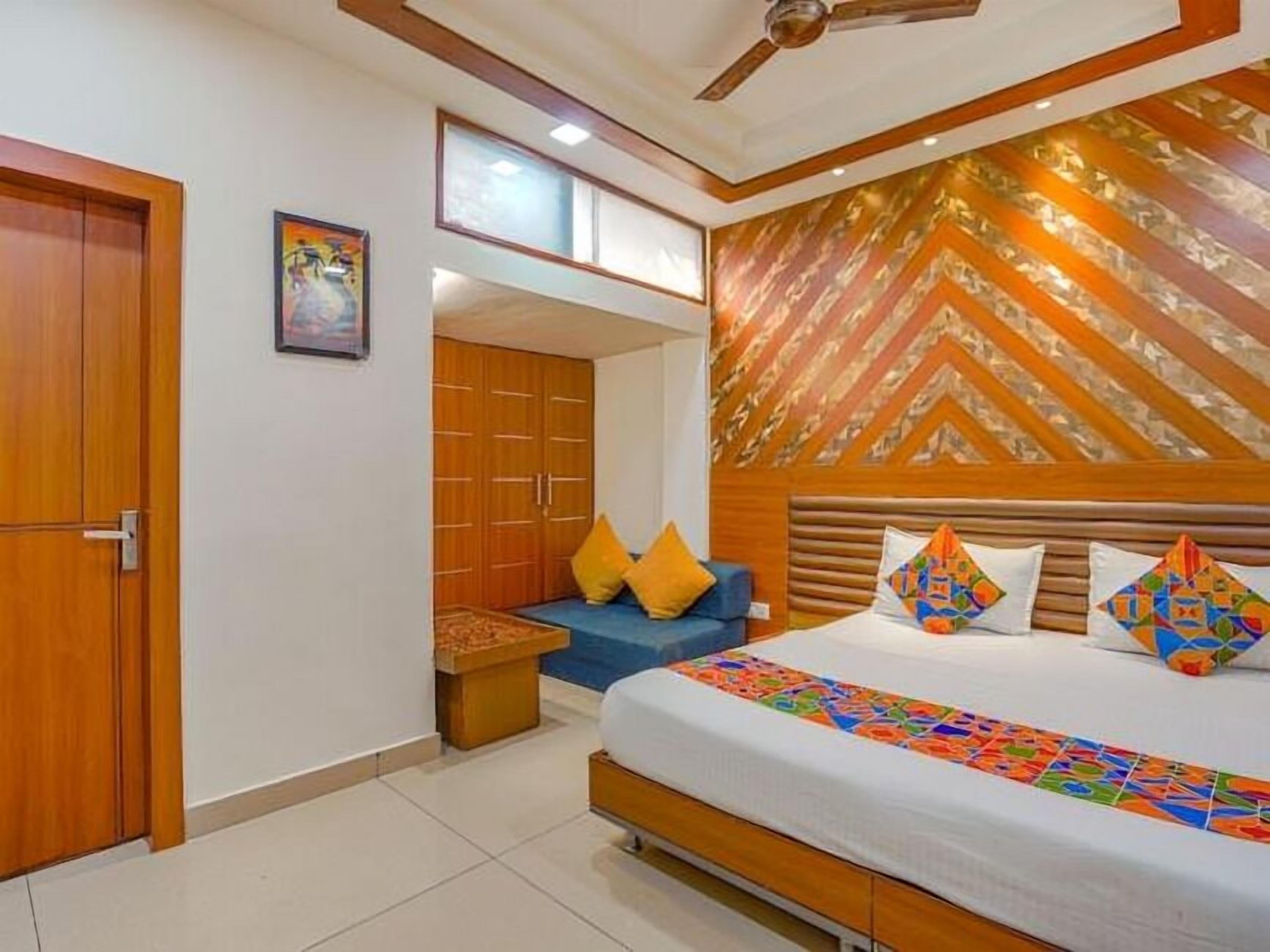 A bedroom with a bed, a ceiling fan, a wardrobe, and a small seating area.