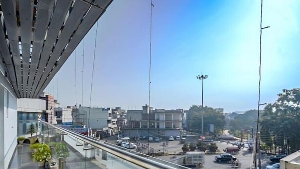 A modern building with a glass balcony overlooking a busy street with cars and buildings. - Hotel 24x7 Inn (Jalandhar)