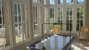 Una mesa de billar en una sala con ventanas amplias y vistas al verdor exterior.