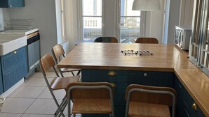 Una cocina con una isla de madera, armarios azules y un ventanal grande.