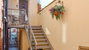 Una escalera con barandillas de metal, un banco de madera y una maceta colgante.