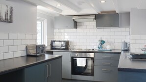 Una cocina moderna con gabinetes grises, salpicadero de azulejos blancos, horno empotrado y microondas.
