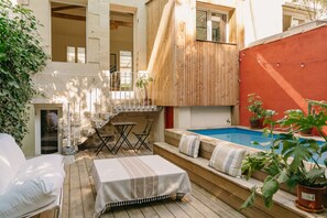 A wooden deck with a pool, outdoor seating, and a staircase leading to an upper level. - Charming renovated house with small pool in the La Bastide district (Bordeaux)