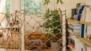 A narrow hallway with a rope net bridge, a potted plant, and a bookshelf filled with books. - Charming renovated house with small pool in the La Bastide district (Bordeaux)