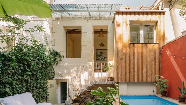 A courtyard with a pool, a wooden deck, a white sofa, and a small staircase leading to an upper level. - Charming renovated house with small pool in the La Bastide district (Bordeaux)