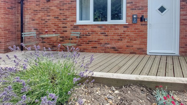 A brick house with a white door, a window, and a small table with chairs. - 1 bedroom accommodation in Walcott (Walcott)