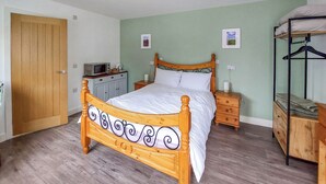 A bedroom with a wooden bed, a bedside table, a nightstand, a wardrobe, a bunk bed, a microwave, and a door. - 1 bedroom accommodation in Walcott (Walcott)