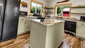 A kitchen with a central island, wooden flooring, and built-in appliances.
