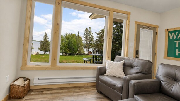 A room with a large window, a brown leather sofa, a wicker basket, and a 'Gone Fishing' sign.