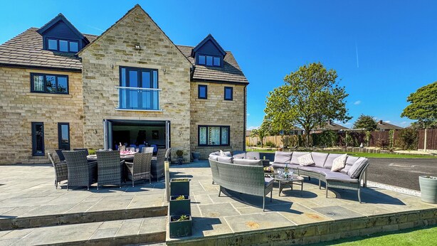 A stone house with a patio, outdoor furniture, and a lawn. - The Old School House (Barnsley)