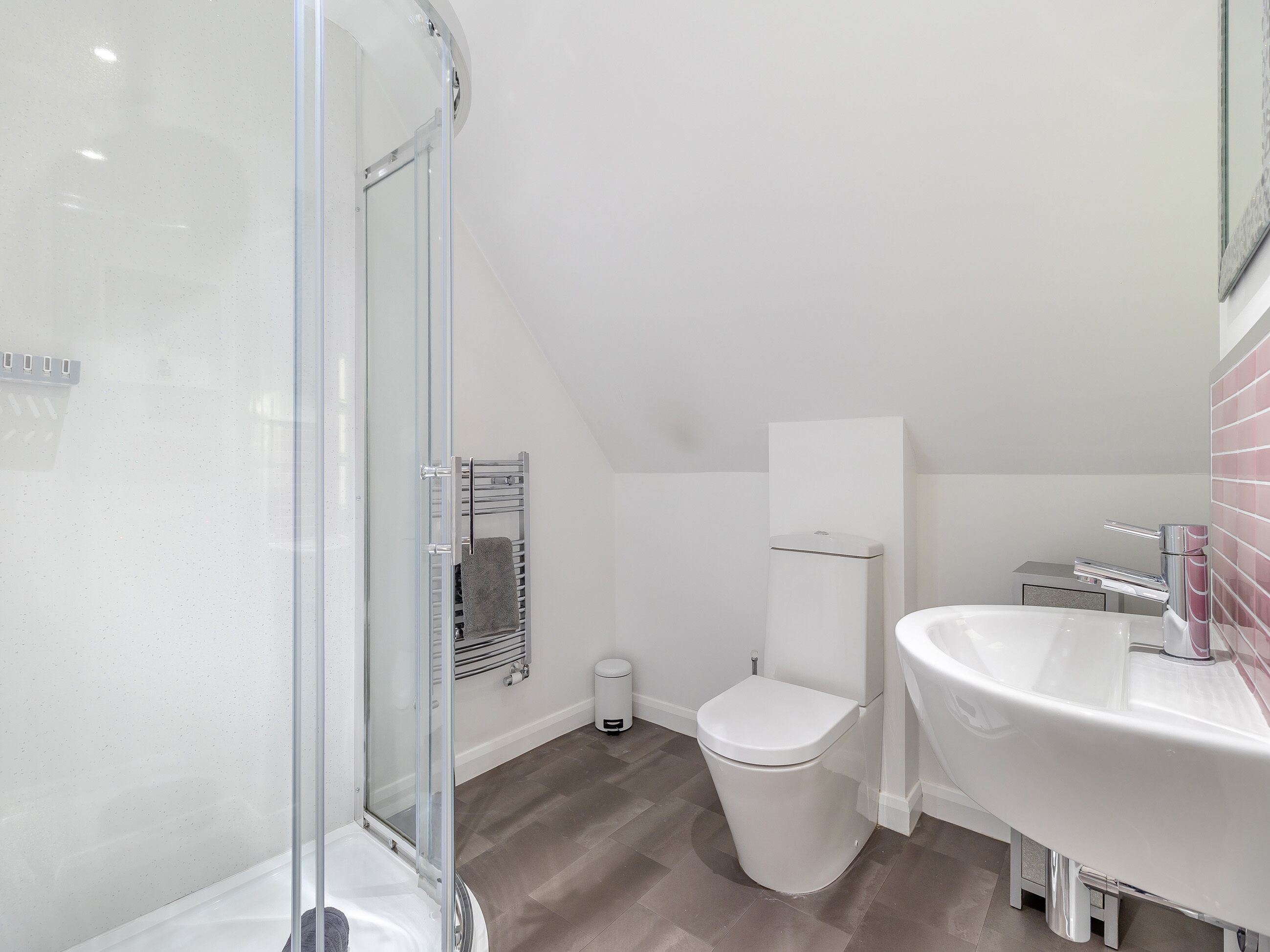 A modern bathroom with a glass shower enclosure, a white toilet, and a sink with a chrome faucet.