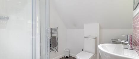 A modern bathroom with a glass shower enclosure, a white toilet, and a sink with a chrome faucet.