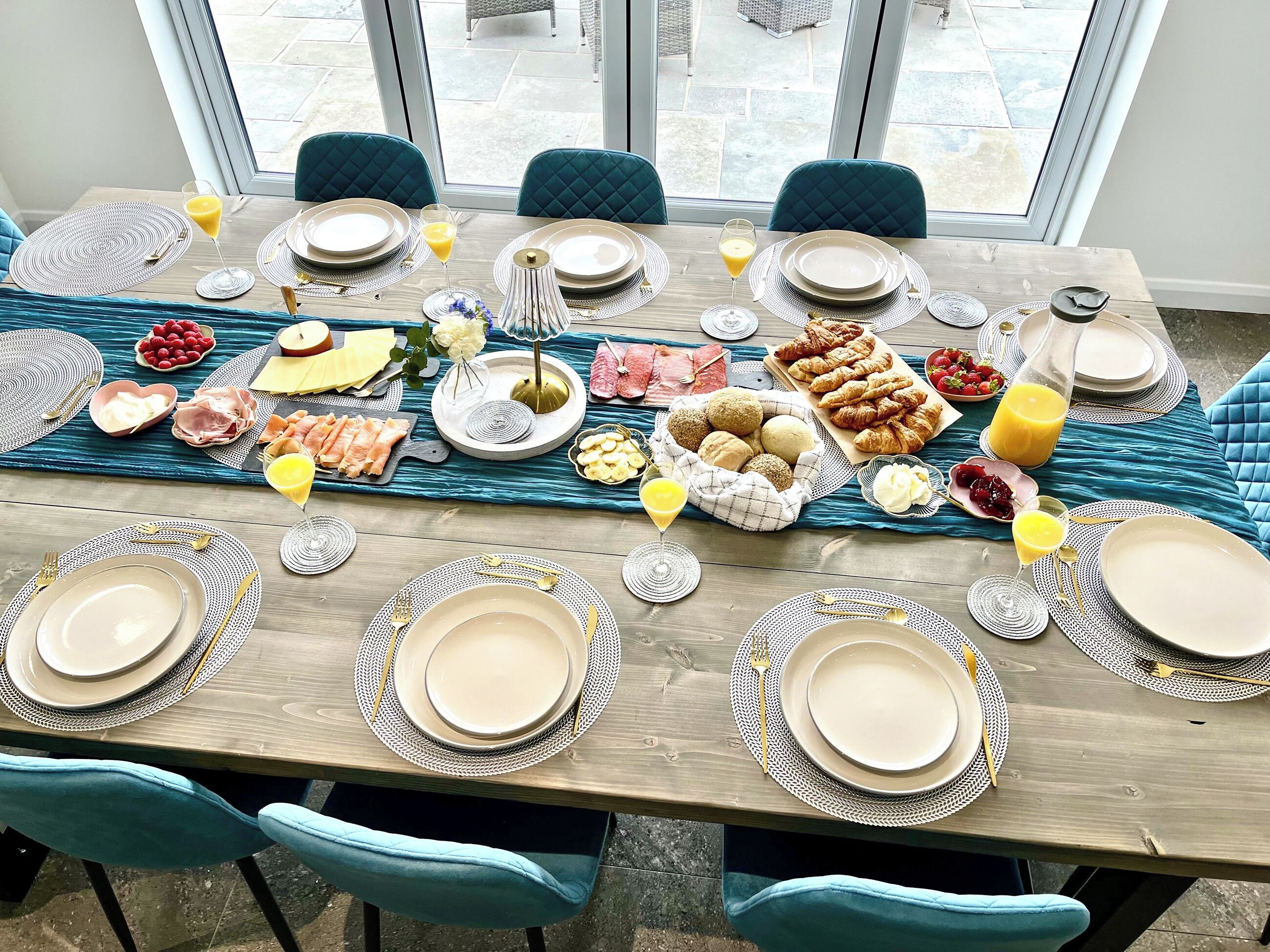 A dining table set for a meal with plates, cutlery, and various food items.