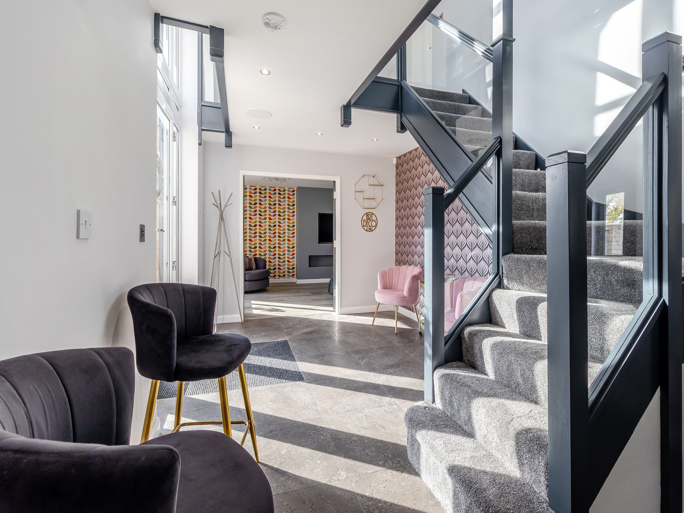 Un intérieur moderne avec un escalier, une chaise noire et un mur à motifs.