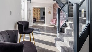 A modern interior with a staircase, a black chair, and a patterned wall. - The Old School House (Barnsley)