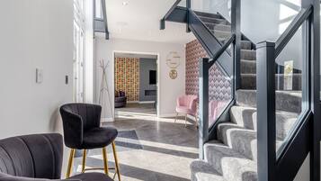 Un intérieur moderne avec un escalier, une chaise noire et un mur à motifs.