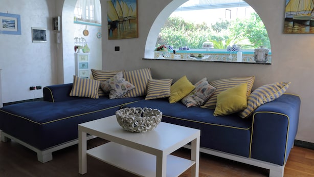 A living room with a blue sofa, white coffee table, and a decorative bowl.