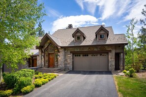 A stone house with a garage, a front porch, and a well-maintained lawn.