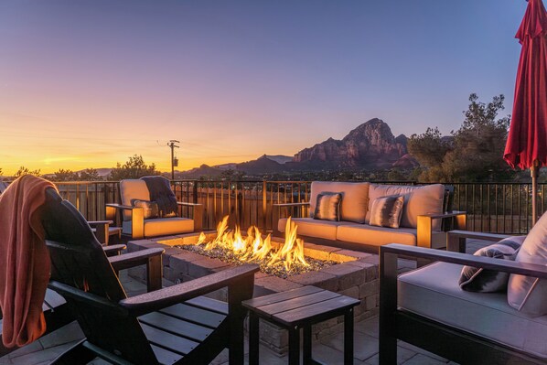 An outdoor seating area with a fire pit, a sofa, and chairs.
