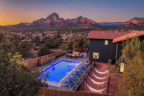 A pool with lounge chairs, a barbecue area, and a mountain view.