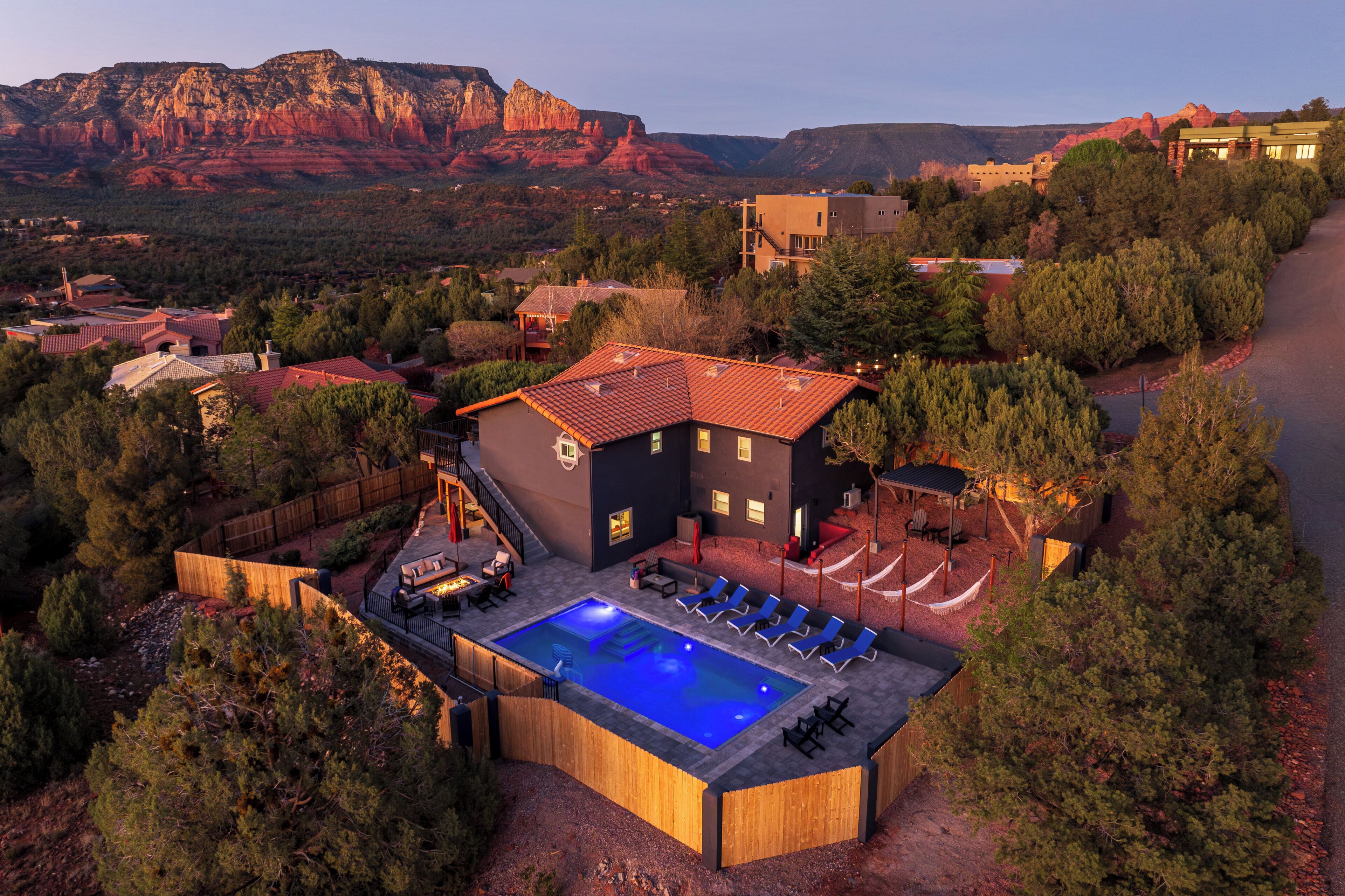 A resort with a swimming pool, lounge chairs, and a view of red rock formations.