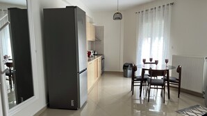 Eine moderne Küche mit einem großen Kühlschrank, Holzschränken und einem Essbereich mit Tisch und Stühlen.