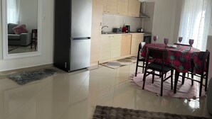 Eine moderne Küche mit Edelstahlkühlschrank, Holzschränken und einer Essecke mit Tisch für vier Personen.